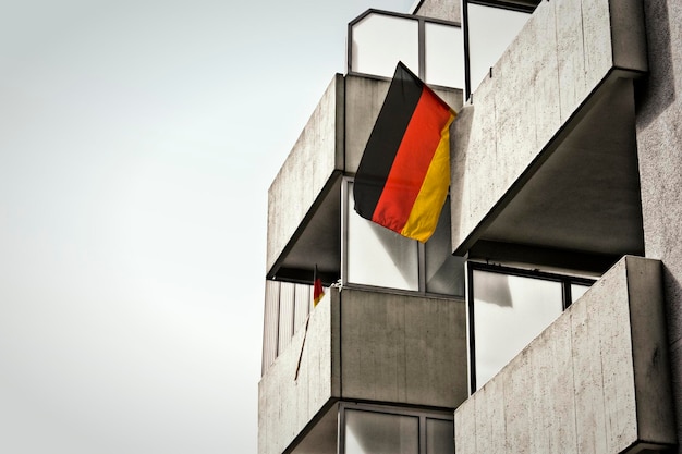 German flag flying in front of a modern glass office building