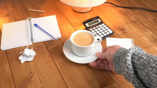 a person reviewing a German salary slip with calculator and coffee